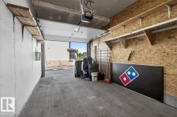 Garage interior with concrete flooring, overhead garage door with automatic opener, wood-finish shelving, and oriented strand board wall finish - 
