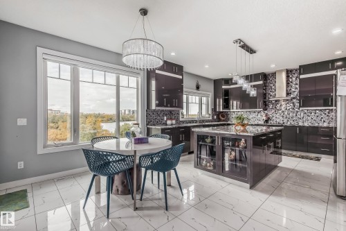 Contemporary kitchen featuring dark cabinetry, a spacious island with display shelving, and a mosaic tile backsplash - 4104 8 Street Nw, Edmonton, AB - Indoor Photo Showing Other Room