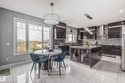 Contemporary kitchen featuring dark cabinetry, a spacious island with display shelving, and a mosaic tile backsplash - 