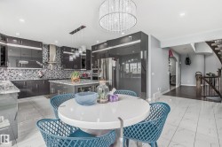 Modern kitchen featuring dark cabinetry, stainless steel appliances, a mosaic tile backsplash, and a central island with countertop seating - 
