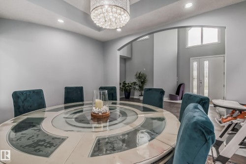 Tray ceiling with recessed lighting and a prominent crystal chandelier - 4104 8 Street Nw, Edmonton, AB - Indoor Photo Showing Dining Room