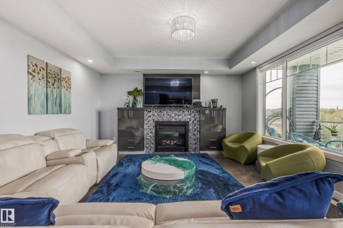 Living room featuring a fireplace with a tiled surround, built-in cabinetry, and wood-finish flooring - 4104 8 Street Nw, Edmonton, AB - Indoor Photo Showing Living Room With Fireplace