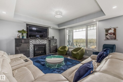 Living room featuring a modern fireplace with mosaic tile surround, built-in cabinetry, and a large window - 4104 8 Street Nw, Edmonton, AB - Indoor Photo Showing Living Room With Fireplace