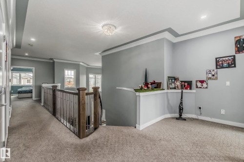 Upper-level landing featuring carpeting, a coffered ceiling with a semi-flush crystal light fixture, white trim, and a wood and metal balustrade - 4104 8 Street Nw, Edmonton, AB - Indoor Photo Showing Other Room