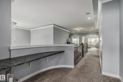 Upper level hallway featuring a decorative built-in shelf, carpet flooring, recessed lighting, and a metal railing - 