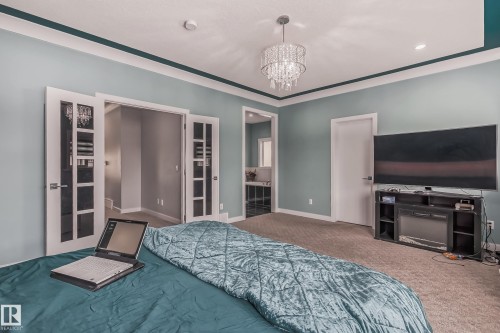 Carpeted interior space featuring a recessed ceiling, crown molding, and a crystal chandelier - 4104 8 Street Nw, Edmonton, AB - Indoor Photo Showing Bedroom