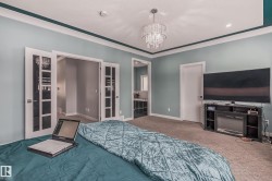 Carpeted interior space featuring a recessed ceiling, crown molding, and a crystal chandelier - 