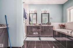Bathroom featuring a double vanity with grey cabinetry and stone countertops - 