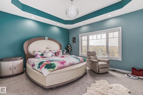 Carpeted room featuring a large window with white trim, a decorative tray ceiling, and recessed lighting - 4104 8 Street Nw, Edmonton, AB - Indoor Photo Showing Bedroom