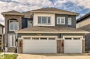 Multi-level residence featuring a two-car garage with transom windows, a stone accent facade, and a prominent arched window on the upper level - 4104 8 Street Nw, Edmonton, AB 