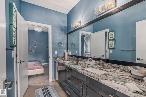 Dual vanity with rectangular undermount sinks, stone countertop, and two sets of wall-mounted light fixtures - 4104 8 Street Nw, Edmonton, AB - Indoor Photo Showing Bathroom