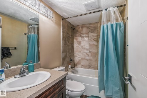 Bathroom featuring a vanity with an undermount sink, a countertop with a stone-finish, and a dark wood-finish cabinet - 4104 8 Street Nw, Edmonton, AB - Indoor Photo Showing Bathroom