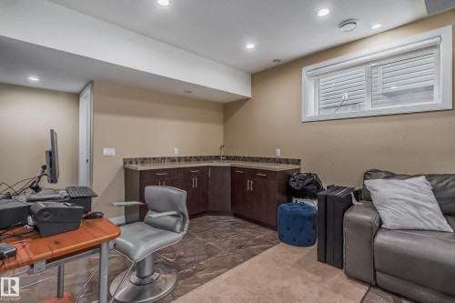 Lower-level space featuring a corner wet bar with a stainless steel sink, dark wood-finish cabinetry, and a tile backsplash - 4104 8 Street Nw, Edmonton, AB - Indoor Photo Showing Other Room