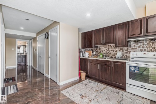 Kitchen featuring dark wood-finish cabinetry, a patterned tile backsplash, and white appliances - 4104 8 Street Nw, Edmonton, AB - Indoor Photo Showing Kitchen