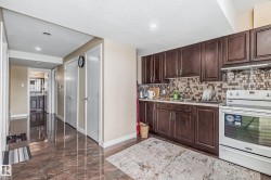 Kitchen featuring dark wood-finish cabinetry, a patterned tile backsplash, and white appliances - 