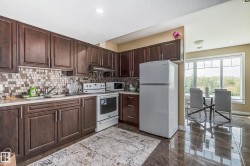 Kitchen featuring dark wood cabinetry, a mosaic tile backsplash, and white appliances - 
