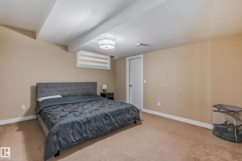 Carpeted room with neutral-toned walls, featuring a window with horizontal blinds - 4104 8 Street Nw, Edmonton, AB - Indoor Photo Showing Bedroom