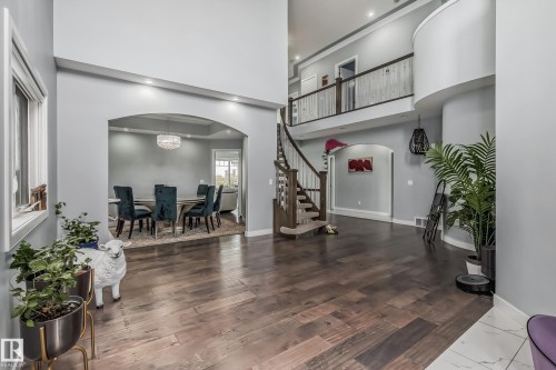 Two-story foyer featuring wood-finish flooring, a curved staircase with wood railings, and a second-story balcony overlooking the entryway - 4104 8 Street Nw, Edmonton, AB - Indoor
