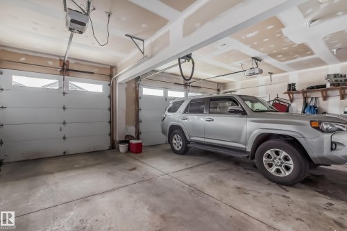 Two-car garage featuring automatic openers and segment-style overhead doors with upper window panels - 4104 8 Street Nw, Edmonton, AB - Indoor Photo Showing Garage