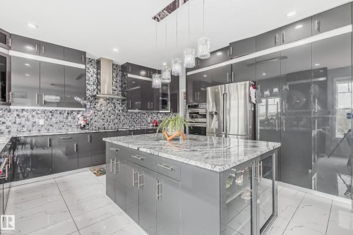 Modern kitchen featuring high-gloss gray cabinetry and a large center island with a stone countertop - 4104 8 Street Nw, Edmonton, AB - Indoor Photo Showing Kitchen With Upgraded Kitchen