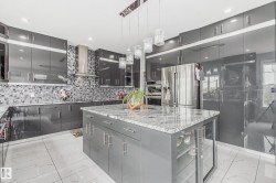 Modern kitchen featuring high-gloss gray cabinetry and a large center island with a stone countertop - 