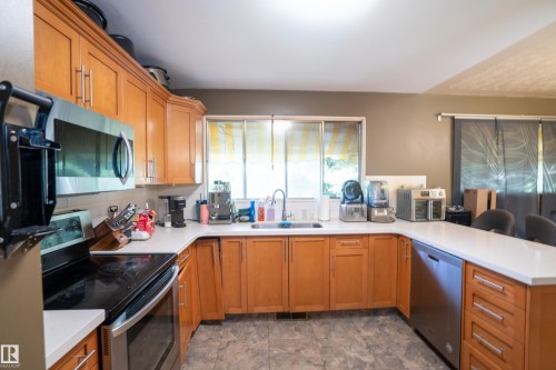 Kitchen featuring wood cabinetry, light countertops, stainless steel appliances, and a window above the sink - 5307 105 Street Nw, Edmonton, AB - Indoor Photo Showing Kitchen