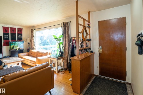 Hardwood flooring extends throughout the living area, featuring a large picture window providing abundant natural light - 5307 105 Street Nw, Edmonton, AB - Indoor