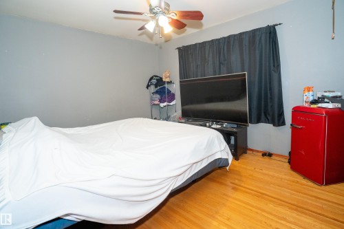 Hardwood flooring with a natural finish, gray painted walls, and a ceiling fan with integrated lighting - 5307 105 Street Nw, Edmonton, AB - Indoor Photo Showing Bedroom