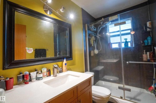 Bathroom vanity with a rectangular undermount sink, a chrome faucet, and a large framed mirror illuminated by track lighting - 5307 105 Street Nw, Edmonton, AB - Indoor Photo Showing Bathroom