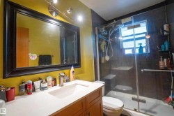 Bathroom vanity with a rectangular undermount sink, a chrome faucet, and a large framed mirror illuminated by track lighting - 