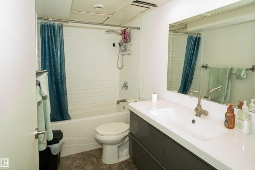 Bathroom featuring a white subway tile shower surround, single vanity with integrated sink, brushed nickel faucet, and a large mirror - 5307 105 Street Nw, Edmonton, AB - Indoor Photo Showing Bathroom