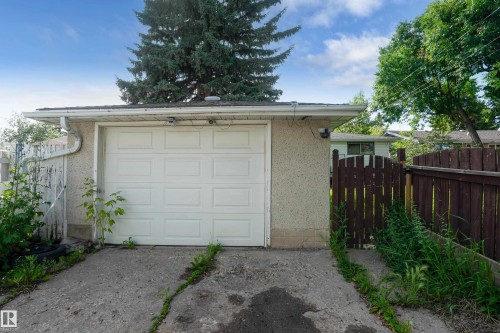 Detached garage structure with a panel-style door, concrete drive, and surrounding wooden fencing - 5307 105 Street Nw, Edmonton, AB - Outdoor