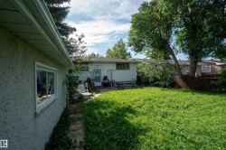 Expansive rear yard featuring green space, mature trees, and a privacy fence - 