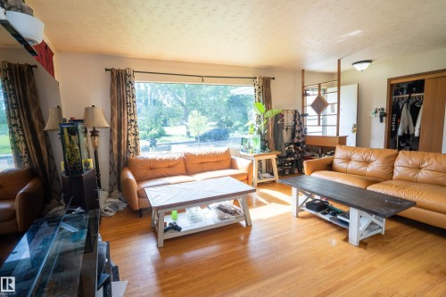 Spacious living area featuring wood-finish flooring, a large picture window, and a built-in closet with sliding doors - 5307 105 Street Nw, Edmonton, AB - Indoor Photo Showing Living Room
