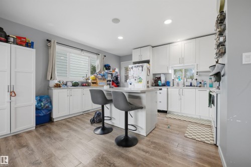 Kitchen featuring wood-finish flooring, white cabinetry, a central island with seating, recessed lighting, and a window above the sink - 4810 55 Avenue, Beaumont, AB - Indoor Photo Showing Kitchen