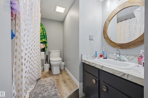Bathroom featuring a vanity with dark cabinetry, an oval undermount sink, and a patterned countertop - 4810 55 Avenue, Beaumont, AB - Indoor Photo Showing Bathroom