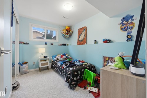 Bedroom featuring light blue walls, a double-paned window, and light-colored carpeting - 4810 55 Avenue, Beaumont, AB - Indoor Photo Showing Bedroom