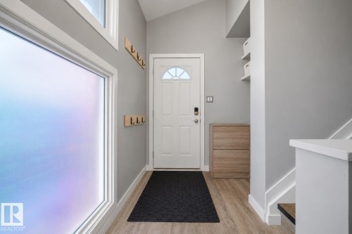 Entryway featuring a light wood-finish floor, a white paneled door with a frosted glass insert, and a transom window - 4810 55 Avenue, Beaumont, AB - Indoor Photo Showing Other Room