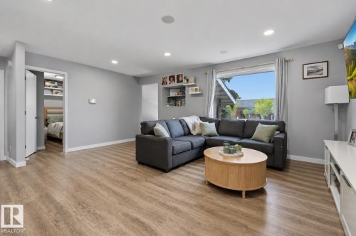 Spacious living area featuring wood-finish flooring, recessed lighting, and a large picture window with curtains - 4810 55 Avenue, Beaumont, AB - Indoor Photo Showing Other Room