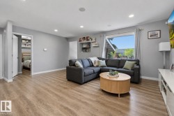 Spacious living area featuring wood-finish flooring, recessed lighting, and a large picture window with curtains - 