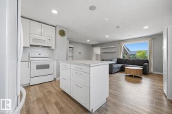 Kitchen featuring white cabinetry, white appliances, a white subway tile backsplash, and a central island with a light-toned countertop - 
