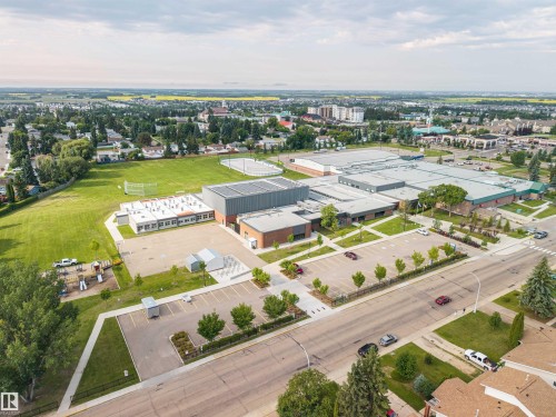 Expansive institutional complex featuring multiple buildings with diverse architectural styles, extensive paved parking areas, and surrounding green spaces including athletic fields - 4810 55 Avenue, Beaumont, AB - Outdoor With View