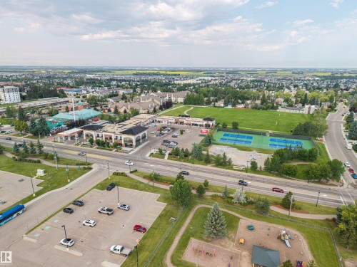 Commercial storefronts featuring arched details, tennis courts, open green spaces, and a playground - 4810 55 Avenue, Beaumont, AB - Outdoor With View