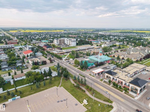 Expansive aerial perspective showcasing a mixed-use neighborhood with residential properties, commercial establishments, and a large paved parking area - 4810 55 Avenue, Beaumont, AB - Outdoor With View