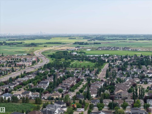 Expansive aerial perspective showcasing a residential neighborhood with varied housing styles, surrounded by green spaces and agricultural fields - 4810 55 Avenue, Beaumont, AB - Outdoor With View