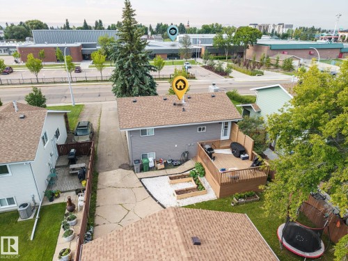 Rear exterior featuring a spacious wood deck, white gravel patio, and raised garden beds - 4810 55 Avenue, Beaumont, AB - Outdoor With Deck Patio Veranda
