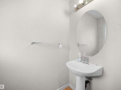 Pedestal sink with chrome faucet, complemented by an oval mirror and overhead vanity lighting - 