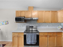 Kitchen featuring wood cabinetry, light-toned countertops, a stainless steel electric range, and a tiled backsplash - 