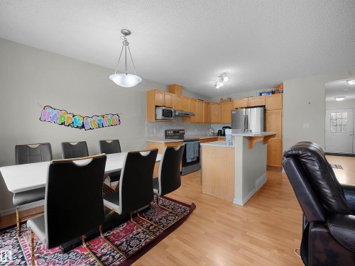 Open-concept kitchen and dining area featuring wood-finish flooring - 8111 7 Avenue Sw, Edmonton, AB - Indoor