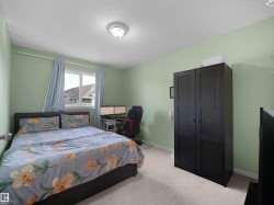 Bright room with soft green walls, featuring a window with natural light, a ceiling-mounted light fixture, and light-colored carpet flooring - 